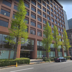 a building with trees and cars parked on the side of the road