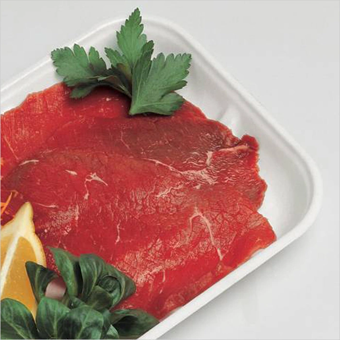a tray of raw meat with lemon and parsley