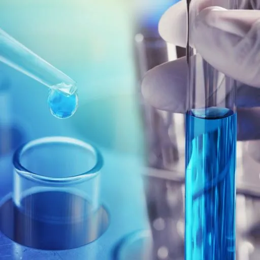 a hand holding a test tube with a drop of blue liquid